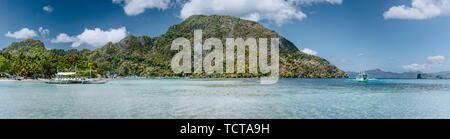 Panoramablick auf die Bucht von El Nido am ruhigen sonnigen Tag. Malerische Küste mit Palmen, Sandstrand und klares Wasser. Einzigartige Natur von Palawan Stockfoto