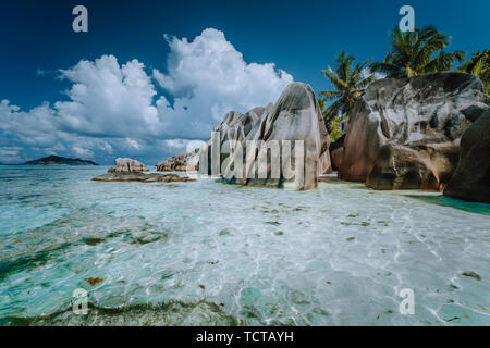 Granit Findlinge im flachen Meer Wasser und weiße cloudscape auf erstaunliche Anse Source D'Argent tropical beach, La Digue Seychellen. Luxus exotische Reisen Stockfoto
