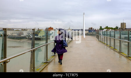 Shoreham-by-Sea, Sussex, UK. 10. Juni 2019. Sonnenschirme sind als Menschen die Adur Fußgängerbrücke über den Fluss Adur in Shoreham heute bei nassem Wetter Kreuz. Es wird prognostiziert, dass Teile der Osten und Südosten ein Monate Niederschlag in den nächsten Tagen in das, was als Monsun Juni genannt wird. Foto: Simon Dack/Alamy leben Nachrichten Stockfoto