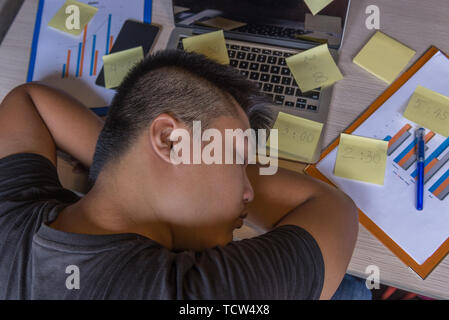 Müde Büro mann Einschlafen, die auf Notebook- und Haftnotizen Stockfoto