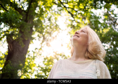 Close up Portrait der älteren Frau, die von dem Baum Stockfoto