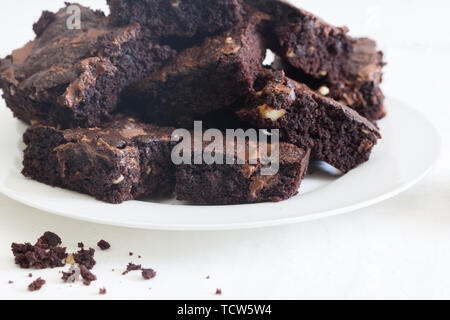 Chocolate brownies in einem Haufen auf einem weißen Teller auf weißem Hintergrund Stockfoto