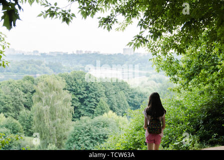 Junge Mädchen für Reisende mit einem kleinen Rucksack, und genießen Sie den atemberaubenden Blick auf die Stadt, Wandern und Ausflüge in die Natur. Erwartung Stockfoto