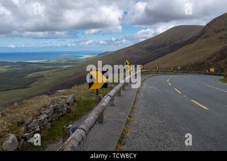 Suche entlang der gewundenen Straße von Conor Pass auf der Halbinsel Dingle, Irland, strahlend blauen Himmel mit Fluffy Clouds, niemand im Bild Stockfoto