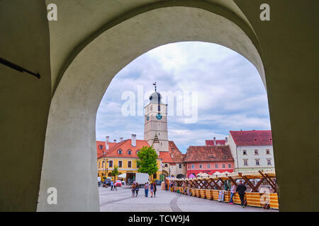 Sibiu, Rumänien - 27. Mai, 2019: Der Rat Turm (Turnul Sfatului) unter einer Passage arch der Künste Haus - Metzger Guild Hall in Hermannstadt gesehen, Romani Stockfoto