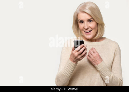 Ältere Frau am Bildschirm des Smartphones Suchen fühlt sich Staunen studio Shot Stockfoto