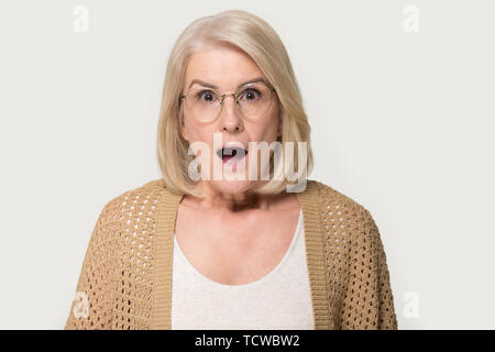 Headshot studio portrait Alter überrascht, schockiert Frau isoliert auf Grau Stockfoto