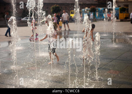 Stadt Brunnen in der Sommerhitze. Kinder laufen und spielen zwischen Wasser fließt Stockfoto