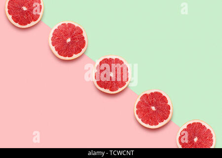 Grapefruit Schichten in Reihe auf Pastell rosa und grünen Hintergrund. Minimale Sommer Konzept. Flach, trendige saftige Farben. Stockfoto