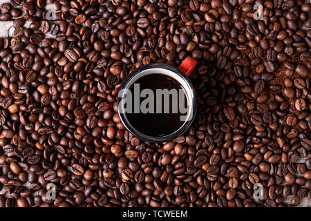 Kaffeebohnen Hintergrund mit einem roten Schale in der Mitte mit frisch zubereiteten Kaffee Stockfoto