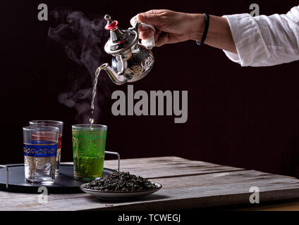 Person Kaffee in einem silbernen Teekanne über Glas Tassen serviert Stockfoto