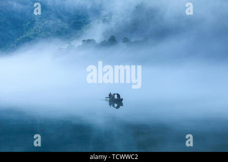 Nebel füllt Xiao Dongjiang 6 (Am frühen Morgen des Sommers, dicker Nebel durchdringt Xiao Dongjiang und in der Licht und Schatten auf den Sonnenaufgang, Fischer bereiten Sie Fisch.) Stockfoto