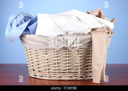 Helle Kleidung in den Wäschekorb, auf farbigem Hintergrund Stockfoto