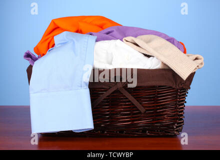 Helle Kleidung in den Wäschekorb, auf farbigem Hintergrund Stockfoto