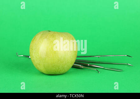 Green Apple und zahnmedizinische Werkzeuge auf farbigen Hintergrund Stockfoto