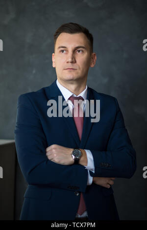 Porträt der jungen intelligenten mann Rechtsanwalt stand mit verschränkten Armen in der modernen Bürogebäude Innenraum, erfolgreichen männlichen Mitarbeiter der Bank gekleidet in Stockfoto