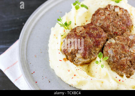 Kartoffelpüree und Fleischbällchen auf grau Platte, mit frischem Basilikum eingerichtet Stockfoto