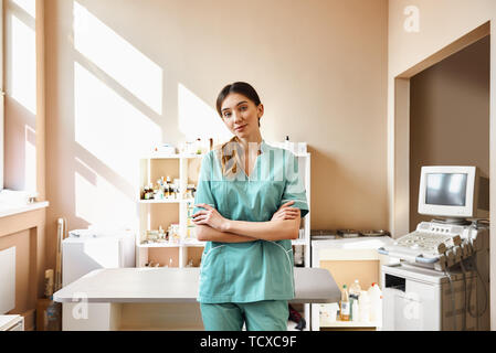 Professionelle Arzt. Portrait von Art und junge weibliche Tierarzt in Arbeit einheitliche stehend mit der Waffe in der Tierärztlichen Klinik gekreuzt. Pet Care Concept. Stockfoto