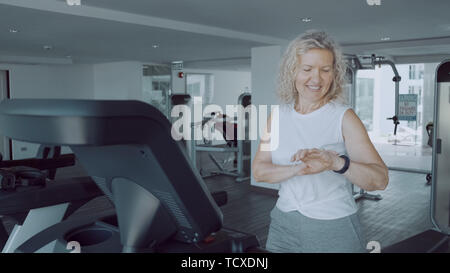 Ältere Frau Sport auf einem Laufband im Fitness-Studio mit einem Sport cardio Watch Stockfoto