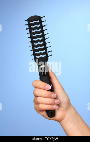 Schwarz Kamm in weiblicher Hand auf farbigen Hintergrund Stockfoto