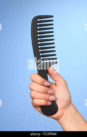 Schwarz Kamm in weiblicher Hand auf farbigen Hintergrund Stockfoto