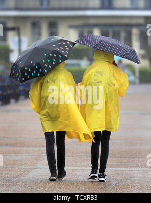 Zwei deutsche Austauschstudenten brave sintflutartige Regenfälle an der Promenade in Eastbourne, Sussex, als die vorhergesagten Regen fegt über den Südosten. Stockfoto