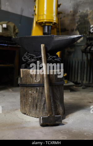 Schweren Vorschlaghammer stützte sich auf Metall Amboss mit Stahl Ketten auf den Stumpf in der Schmiede Werkstatt behoben Stockfoto