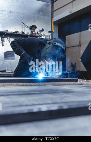 Industrielle Arbeiter Tragen von Helm und Handschuhe schweißen Stahlbau im Werk. Vertikaler Dampfstoß Stockfoto
