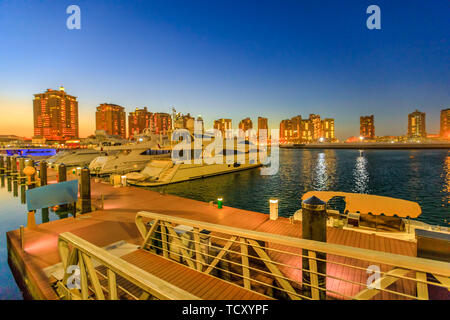 Luxuriöse Yachten und Boote angedockt in Porto Arabien Marina in der Nacht. Die Pearl-Qatar in Doha ist eine künstliche Insel, Symbol der Stadt und ein beliebtes Stockfoto