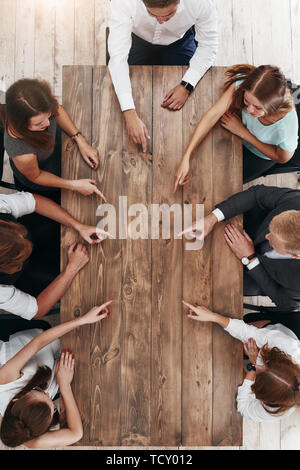 Blick von oben auf die Sitzung für das Business Team, Brainstorming auf das neue Projekt. Mitarbeiter sitzen an den braunen Holzschreibtisch. Kollegen zeigen Stockfoto