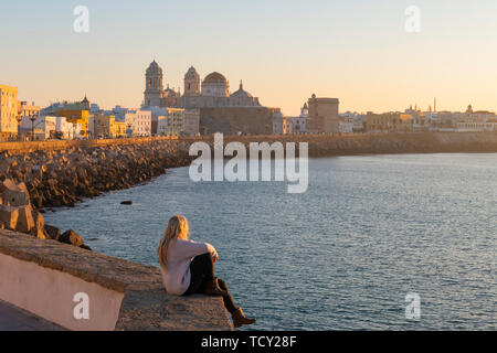 Frau genießen den Blick auf die Kathedrale von Santa Cruz und das Meer von der Promenade entlang Kai, Cadiz, Andalusien, Spanien, Europa Stockfoto