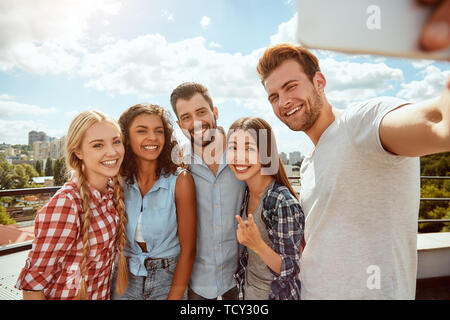 Sammeln von glücklichen Momenten. Sind eine Gruppe von fröhlichen und junge Menschen, die selfie und lächelnd an Kamera und stehen auf dem Dach. Sommer Konzept. Havin Stockfoto