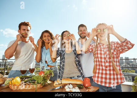 Zeit mit Freunden. Gruppe von Jungen und Fröhlichen Freunden in Freizeitkleidung Vorbereiten der Nahrung für die Grillparty und Spaß beim Stehen auf t Stockfoto