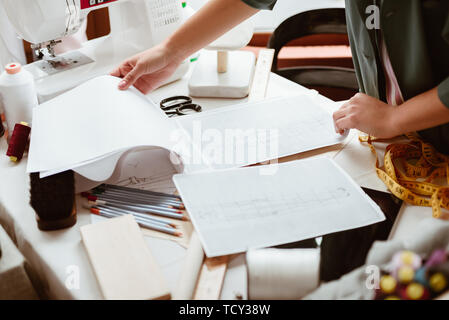 Ideen in Kleidung. Junge Frau Schneider mit Block und Bleistift ist Modellierung neue Kleidung im Design Studio. Close-up Stockfoto