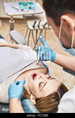 Männlicher Arzt mit Einspritzung. Junge Zahnarzt spritzt Anästhesie vor der Operation. Geduldig wartet auf Sie. Zahnärztliche Behandlung. Vertikale erschossen. Hohen Winkel Stockfoto