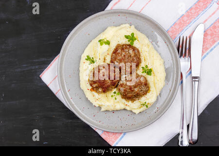 Kartoffelpüree und Fleischbällchen auf grau Platte, mit frischem Basilikum eingerichtet Stockfoto