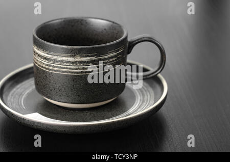 Graue Tasse und Untertasse Auf einem Schwarzen Tisch. Schließen oben mit geringer Tiefenschärfe Stockfoto