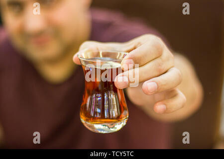 Türkische Mann hält aus schwarzen Türkischen Tee im traditionellen Glas Stockfoto