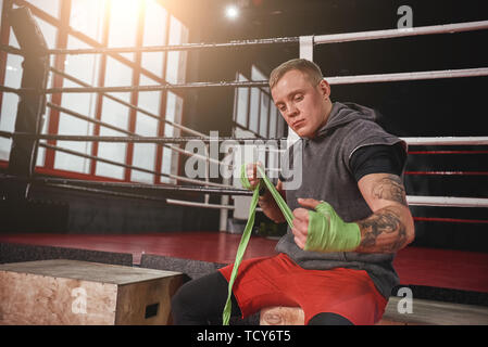 Boxing Verteidigung. Zuversichtlich athletischen Mann einwickeln Händen grüne Boxen Wraps in Boxing Gym. Starke Hände und Faust bereit für den Kampf Stockfoto