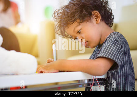 Asian Boy mit einem Magic Pen auf das Schreiben auf Notebook und am Nachmittag. Stockfoto