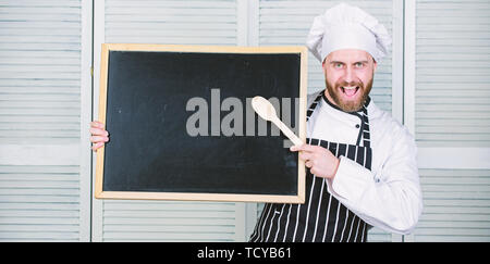 Lehre die Studenten, wie man kocht. Chief cook Lehre Master Class in der Kochschule. Master kochen, Kochkurs. Kulinarische Ausbildung. Mann, Löffel aus Holz an der leeren Tafel, kopieren. Stockfoto