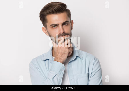 Nachdenklichen jungen Mann die Hand am Kinn Gefühl zweifelhaft Stockfoto