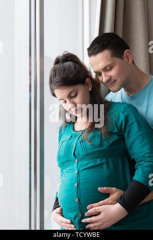 Neue aufgeregt Eltern liebevoll Holding ungeborenes Kind durch Fenster Stockfoto