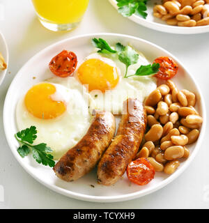 Teller zum Frühstück mit gebratenen Würstchen, Eier, Bohnen, Tomaten, grüne auf die Platte über der weißen Stein Hintergrund Stockfoto