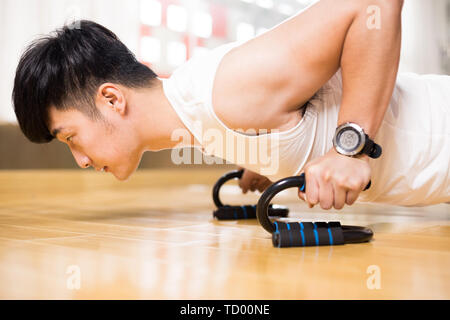 Die Jungen gut aussehenden asiatischer Mann arbeitet sie im modernen Fitnessraum Stockfoto