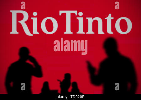 Die Rio Tinto Logo ist auf einen LED-Bildschirm im Hintergrund, während eine Silhouette Person ein Smartphone verwendet im Vordergrund (nur redaktionelle Nutzung) Stockfoto