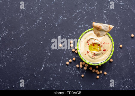 Gesundes Essen. Pflanzliche Proteinquellen. Schüssel mit Hummus, auf schwarzen Steintisch, Kichererbsen. Stockfoto