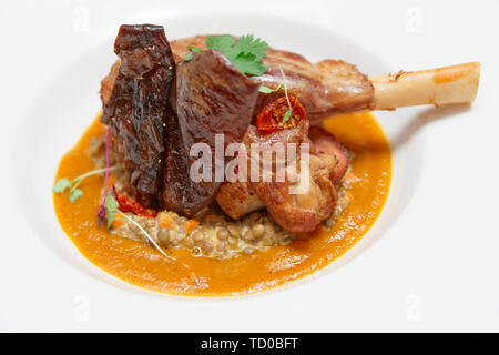 Lamm Bein mit Linsen und Zucchini in der Platte, close-up Stockfoto