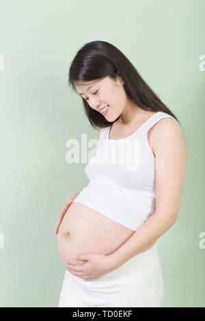 Foto der hübschen schwangeren Frau ihre Hände auf dem Bauch halten. Stockfoto