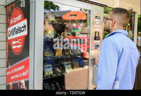 Wedemark, Deutschland. 07 Juni, 2019. Ein Mann steht vor einem Automaten im grimsehl Metzger wo Grill Fleisch und Wurst verkauft werden. Kleine Einzelhändler nicht mit den Öffnungszeiten von Supermärkten oder Tankstellen. Sie können aber auch ihre Waren am Abend und an Feiertagen mit Automaten verkaufen. Credit: Christophe Kirschtorte/dpa/Alamy leben Nachrichten Stockfoto
